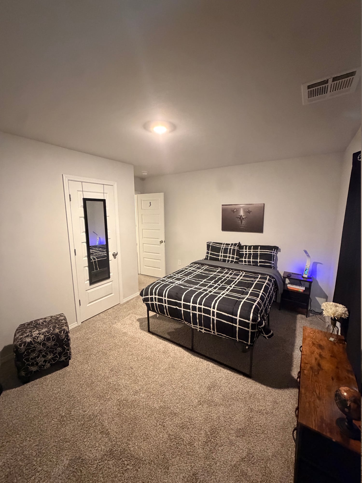 Bedroom with checked bedding, bedside table, and storage