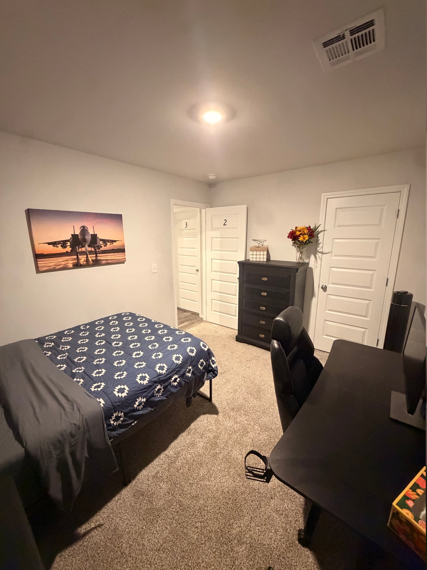 Bedroom with blue bedding, dresser, and a study desk