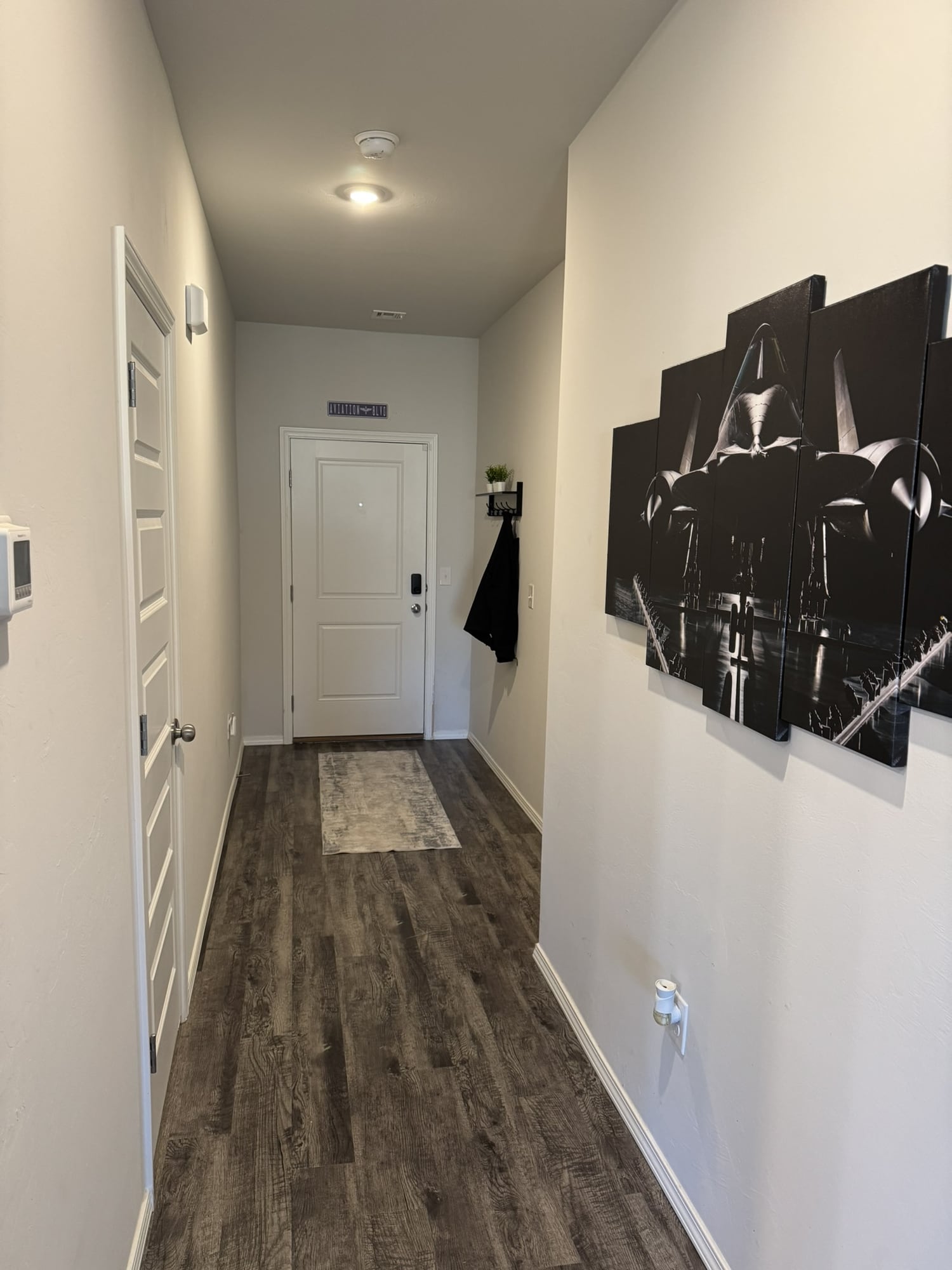 Front entry hallway with wood-look flooring and aviation wall art